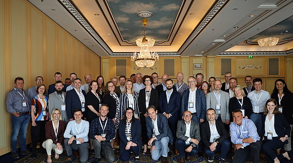 Group photo with several people, within a room with a big chandelier.